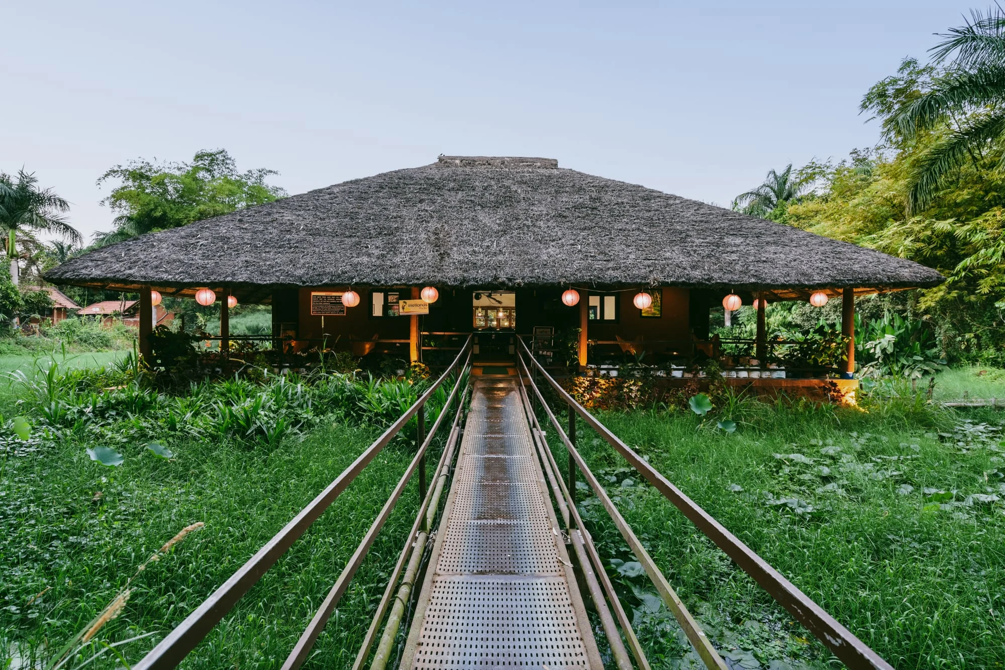 A bridge crossing a green wetland toward the Red Earth pavilion