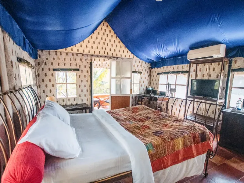 A colourful cottage bedroom beneath a blue canopy