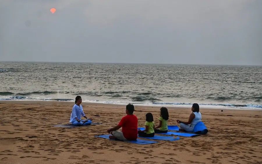 Picture of a family relaxing by meditating on a beach at a resort in gokarna